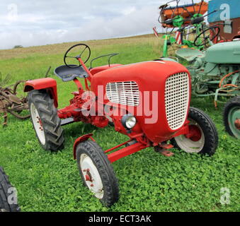 Nahaufnahme von roten antiken Traktor auf dem grünen Rasen von bewölkten Tag Stockfoto