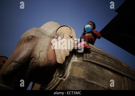 Ein Junge Aufblasen eines Ballons und sitzen auf einem geschnitzten Elefanten in Nyatapola Tempel errichtet von nepalesischen König Bhupatindra Malla im Jahre 1702 in der Stadt Bhaktapur auch als Khwopa in Nepal bekannt Stockfoto