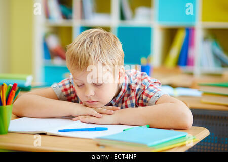 Süsser Boy Nickerchen vom Schreibtisch im Klassenzimmer Stockfoto