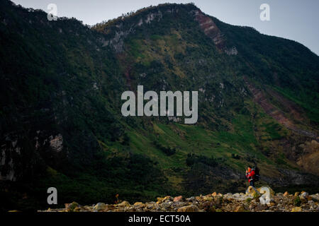 Ein Bergsteiger in rote Jacke mit der Caldera-Wand des Mount Papandayan im Hintergrund. Stockfoto