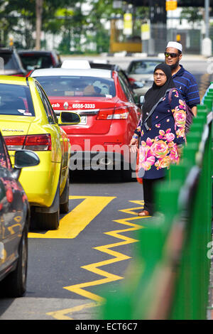Islamische Paar zu Überqueren einer verkehrsreichen Straße auf Büffel Road, Little India, Singapur warten. Stockfoto