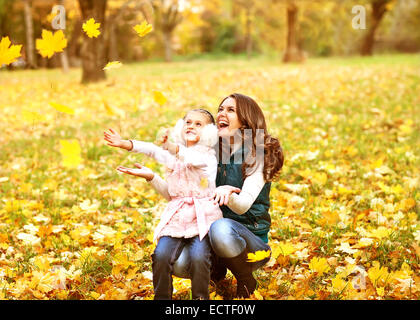 Mutter und Tochter Spaß im Herbst Park unter den fallenden Blättern. Stockfoto