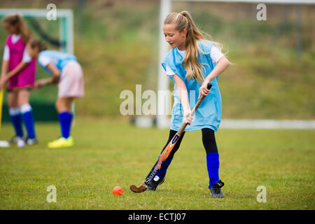 Mittelschule PE Sportunterricht Wales UK: junge 13 14 jährige Mädchen im Teenageralter fangen Sie Hockey auf einem Spielfeld Schule draußen spielen Boden Tonhöhe Stockfoto