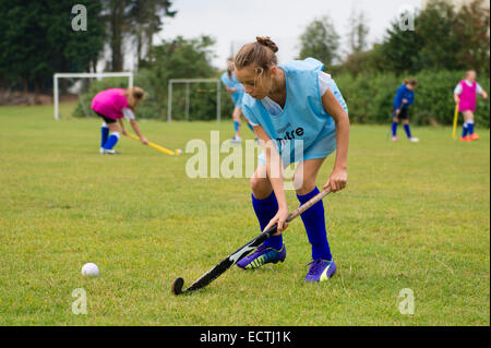 Mittelschule PE Sportunterricht Wales UK: junge 13 14 jährige Mädchen im Teenageralter fangen Sie Hockey auf einem Spielfeld Schule draußen spielen Boden Tonhöhe Stockfoto