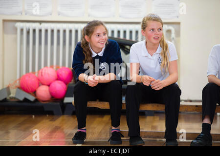 Höhere Schulbildung Wales UK: zwei Mädchen im Teenageralter beobachten andere beim Spielen in der Turnhalle der Schule Stockfoto