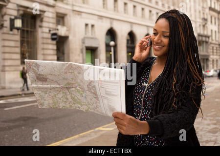 Frau am Telefon mit einer Karte nach dem Weg fragen. Stockfoto