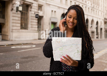 junge Frau am Telefon mit einer Karte. Stockfoto