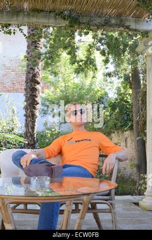 Mann saß gekreuzt Beinen trägt eine Orange 29. Venedig Marathon t-Shirt Stockfoto