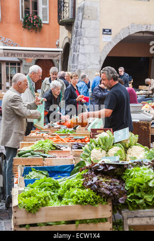 Männliche französische Standbesitzer Dienst am Kunden an ein frisches Gemüse und Salat Stand in einem beliebten lokalen outdoor-Food-Markt in der Altstadt, Annecy, Frankreich Stockfoto
