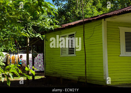 Lachende Frau hängen die Kleider im Hinterhof ein grünes Holz Haus Dominikanische Republik Stockfoto