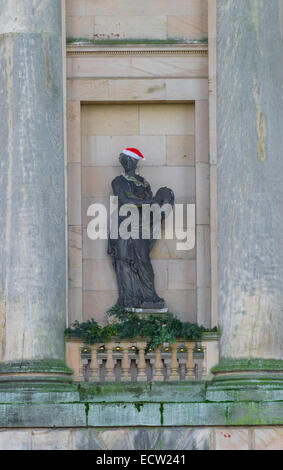 Führen Sie Statue von John Cheere einer Muse in einem steinernen Nischen und mit Santa Claus Hut und Lametta Stockfoto