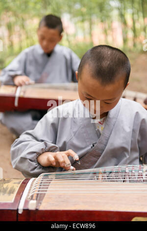 Lizenz erhältlich unter MaximImages.com - Junge Schüler einer Shaolin-Kampfsportschule, die Guzheng spielen lernen, chinesischer Zither in Dengfeng, Henan, CH Stockfoto