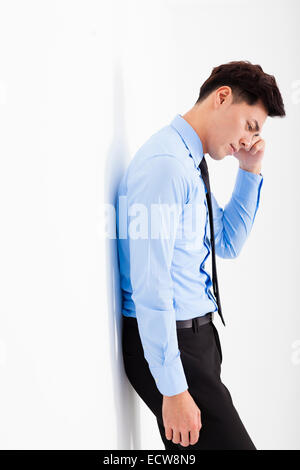 deprimiert junger Geschäftsmann lehnt an der Wand im Büro