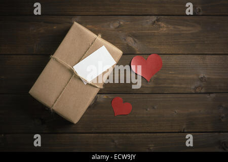 eingewickelt in Kraft Papier Geschenk zum Valentinstag mit roten Herzen Stockfoto
