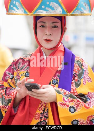 Frau im traditionellen Ryukyu Tanzkostüm mit Hanagasa Hut mit iPhone. Shuri Schlossfest statt in Okinawa Naha City. Stockfoto