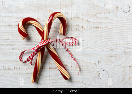 Nahaufnahme von zwei alten altmodischen Zuckerstangen auf einem rustikalen Holztisch weiß getünchten. Die Leckereien sind gekreuzt und mit Band gebunden Stockfoto