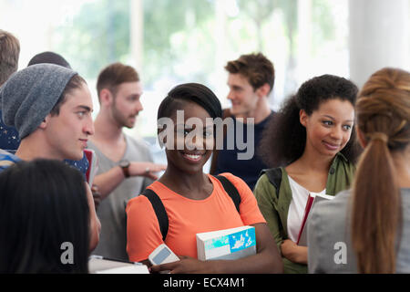 Universität Schüler tragen Buch lächelnd und Blick in die Kamera Stockfoto