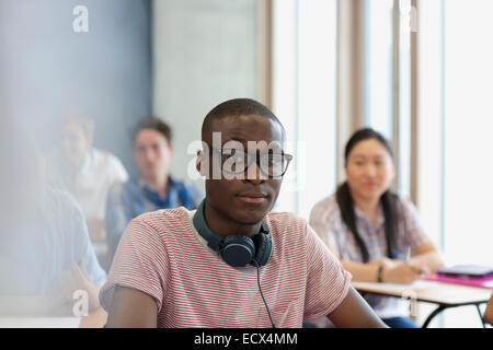 Männliche Studenten mit Brille und Kopfhörer um Hals, Blick in die Kamera während der Vorlesung Stockfoto