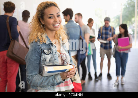 Studentin halten Bücher und Blick in die Kamera Lächeln Stockfoto