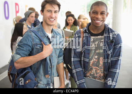 Zwei männliche Studenten mit anderen Studenten im Hintergrund in die Kamera Lächeln Stockfoto