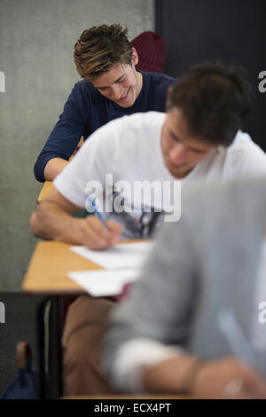 Blick lächelnder Studenten sitzen am Schreibtisch während einer Prüfung im Klassenzimmer Stockfoto