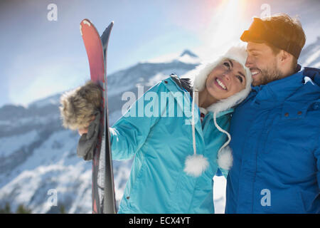 Paar mit Ski umarmt am Berg Stockfoto