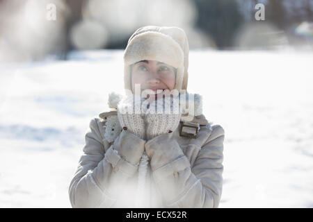 Frau in warme Kleidung lächelnd im Schnee Stockfoto