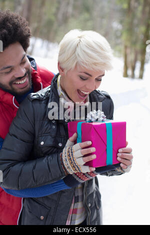 Mann Frau mit Weihnachtsgeschenk im Schnee überrascht Stockfoto