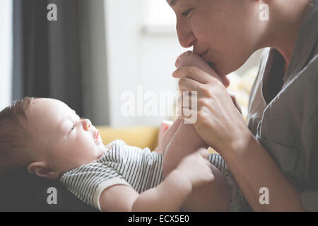 Mutter hält und kleine Babys Füße küssen Stockfoto
