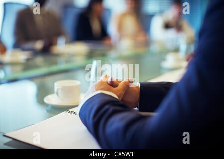 Geschäftsmann, sitzen am Konferenztisch im Konferenzraum mit den Händen umklammert Stockfoto