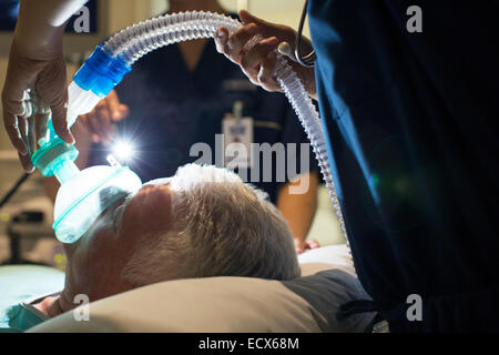 Ärztin mit Maske und betäubende älteren Patienten in der Chirurgie Stockfoto