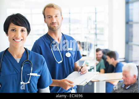 Porträt der Ärzte mit Patienten, die medizinische Behandlung im Hintergrund Stockfoto