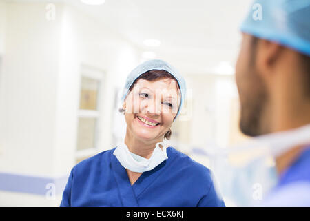 Ärzte tragen chirurgische Kappen im Krankenhausflur stehen und reden Stockfoto
