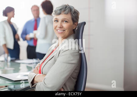 Porträt der Geschäftsfrau in Sessel sitzend mit verschränkten im Konferenzraum Stockfoto