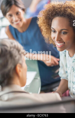 Lächelnde Unternehmerinnen im Konferenzraum im Gespräch Stockfoto