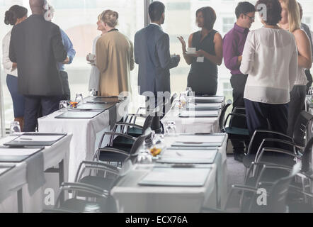 Business-Leute halten Kaffeetassen und diskutieren im Konferenzraum Stockfoto