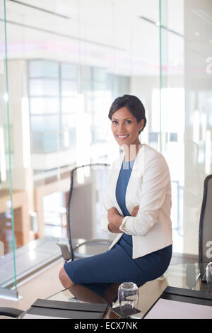 Porträt der schönen lächelnden Geschäftsfrau sitzen am Tisch aus Glas im Konferenzraum Stockfoto