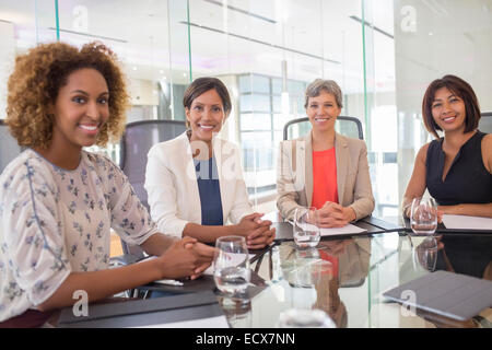 Porträt von vier fröhliche Frauen am Konferenztisch sitzen Stockfoto