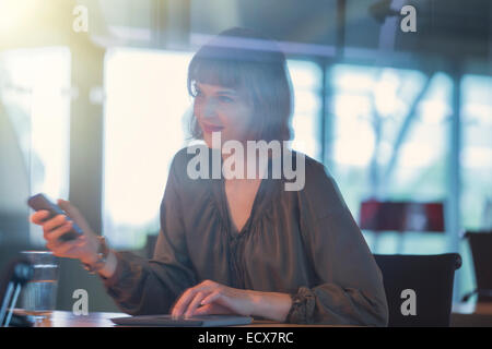 Geschäftsfrau hält Handy am Schreibtisch Stockfoto