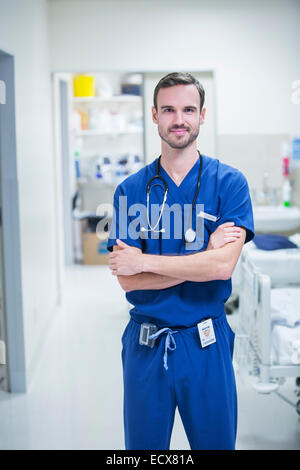 Porträt des jungen männlichen Arzt im Krankenhaus mit verschränkten Armen stehen Stockfoto