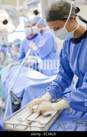Krankenschwester Stand von Tablett mit chirurgischen Instrumenten im Operationssaal Stockfoto