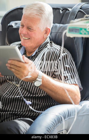 Senior woman mit TabletPC während des Empfangs intravenöse infusion Stockfoto