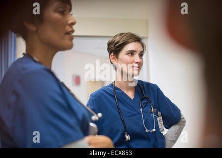 Zwei weibliche Ärzte tragen dunkelblaue Peelings, sprechen im Krankenhaus Stockfoto