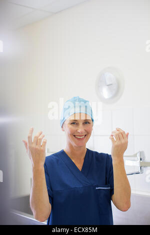 Porträt von lächelnden Ärztin tragen chirurgische Mütze und Mantel im Krankenhaus Stockfoto