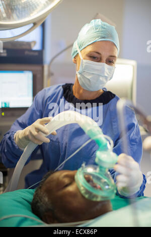 Anästhesist mit Sauerstoffmaske über Gesicht des Patienten im Operationssaal Stockfoto