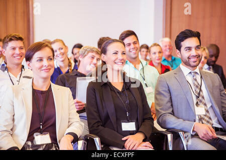 Business-Leute sitzen im Konferenzraum, lächelnd und wegsehen Stockfoto