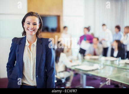 Porträt des jungen Geschäftsfrau lächelnd im Konferenzraum, Menschen im Hintergrund Stockfoto