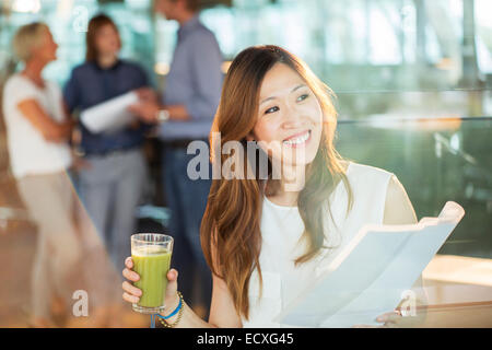 Geschäftsfrau Saft zu trinken und Papierkram im Büro lesen Stockfoto