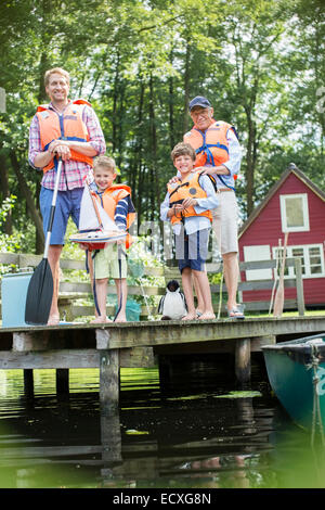 Brüder, Vater und Großvater das Tragen von Schwimmwesten am See Stockfoto