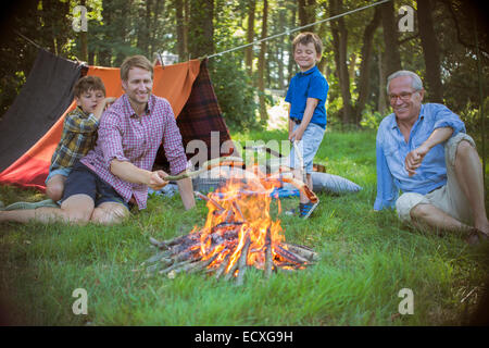 Junge, Vater und Großvater in der Nähe von Lagerfeuer entspannen Stockfoto